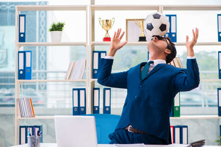 Businessman playing football in the officeの写真素材