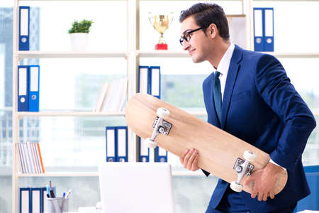 Businessman with skateboard in officeの写真素材