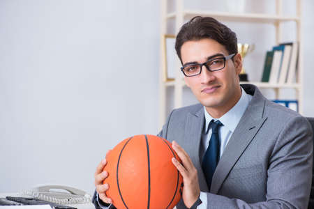 Young businessman playing basketball in office during breakの写真素材