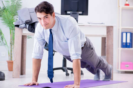 Businessman doing sports in office during breakの写真素材