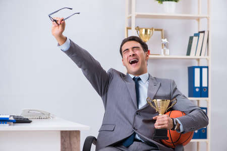 Businessman with prize cup for achievements in officeの写真素材