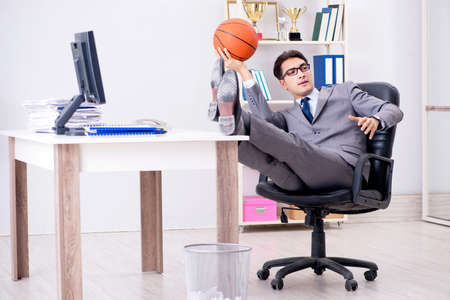 Young businessman playing basketball in office during breakの写真素材