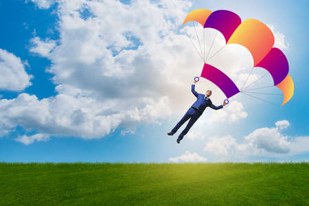 Young businessman falling on parachute in business conceptの写真素材