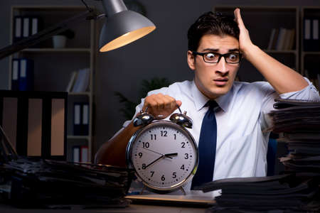 Young businessman working overtime late in officeの写真素材