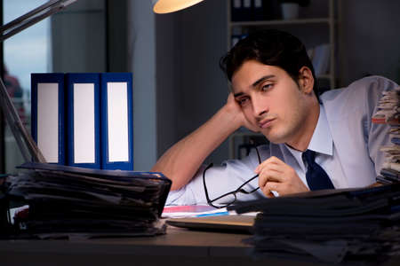 Young businessman working overtime late in officeの写真素材
