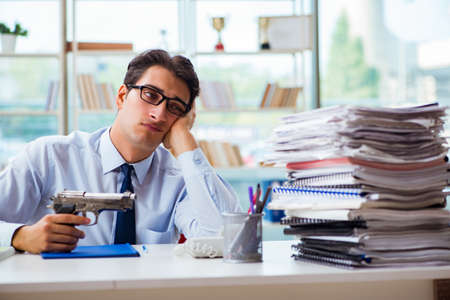 Angry businessman with gun thinking of committing suicideの写真素材