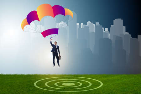 Young businessman falling on parachute in business conceptの写真素材