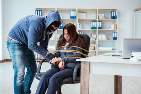 Criminal taking businesswoman as hostage in officeの写真素材