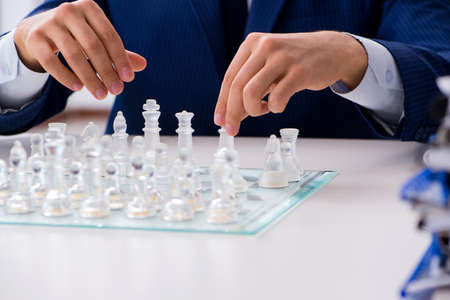 Young businessman playing glass chess in office