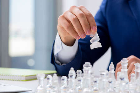 Young businessman playing glass chess in office
