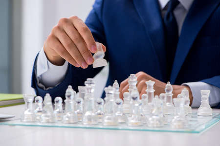 Young businessman playing glass chess in officeの写真素材