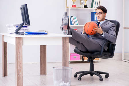 Young businessman playing basketball in office during breakの写真素材