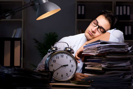 Young businessman working overtime late in officeの写真素材