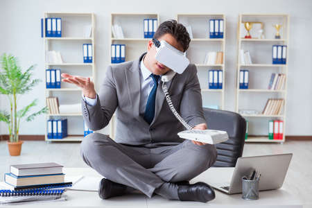 Businessman in virtual reality VR glasses meditating at desk topの写真素材