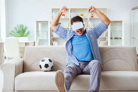 Man wearing virtual reality VR glasses watching soccer footballの写真素材
