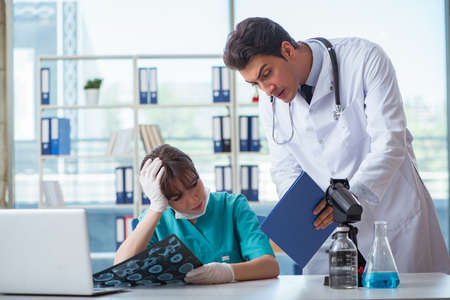 Two doctors discussing x-ray MRI image in hospitalの写真素材