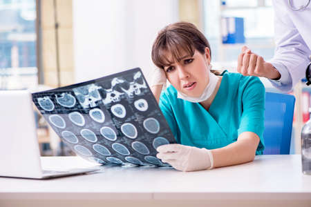 Two doctors discussing x-ray MRI image in hospitalの写真素材