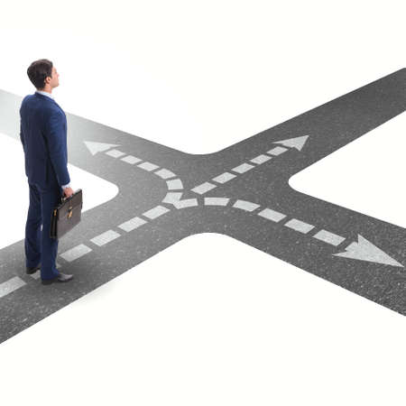 Young businessman at crossroads in uncertainty conceptの写真素材