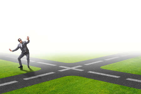 Young businessman at crossroads in uncertainty conceptの写真素材