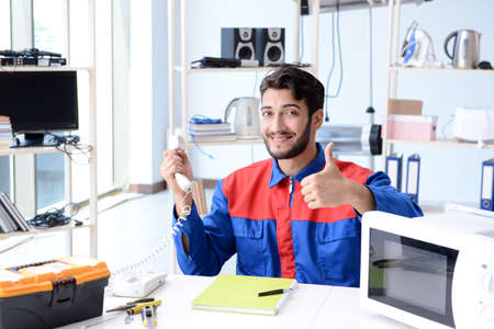 Young repairman fixing and repairing microwave ovenの写真素材