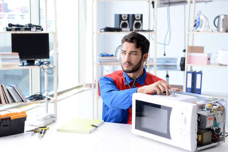 Young repairman fixing and repairing microwave ovenの写真素材