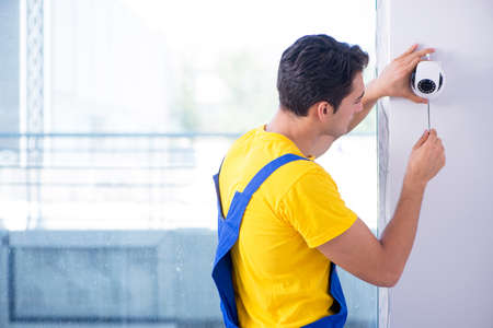 Contractor installing surveillance CCTV cameras in officeの写真素材