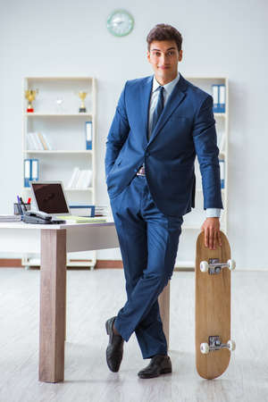 Young businessman with skate in office in sports conceptの写真素材