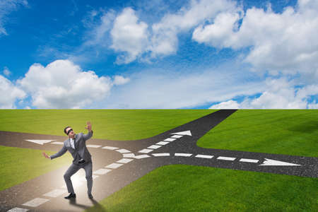 Young businessman at crossroads in uncertainty conceptの写真素材