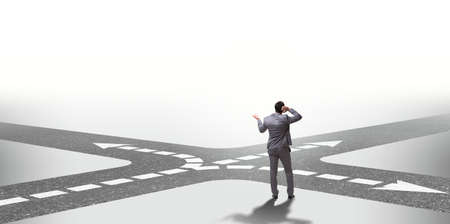 Young businessman at crossroads in uncertainty conceptの写真素材