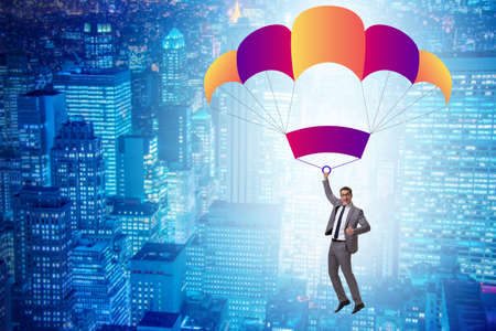Young businessman falling on parachute in business conceptの写真素材
