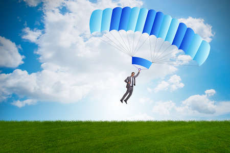Young businessman falling on parachute in business conceptの写真素材