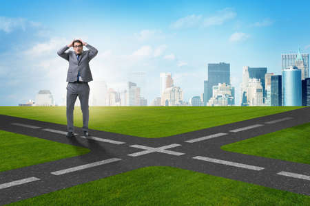 Young businessman at crossroads in uncertainty conceptの写真素材
