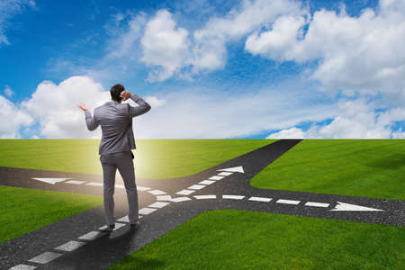 Young businessman at crossroads in uncertainty conceptの写真素材