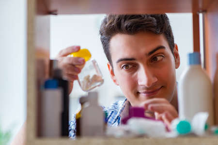 Sick ill man looking for medicines at farmacy shelfの写真素材