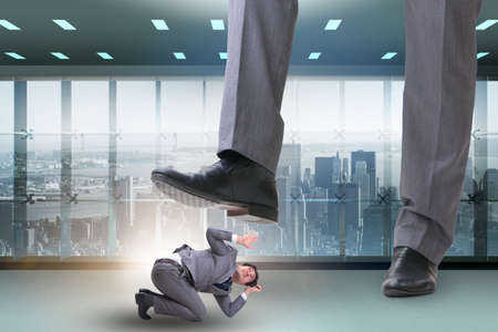 Bad angry boss stamping on employee in business concept