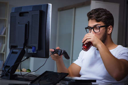 Young man playing games long hours late in the officeの写真素材