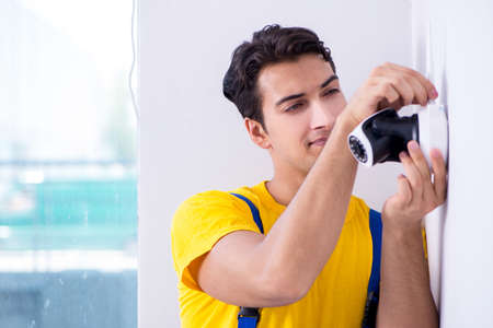 Contractor installing surveillance CCTV cameras in officeの写真素材