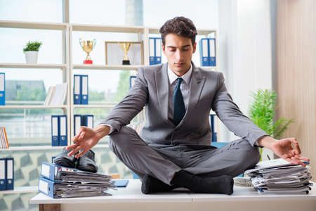 Businessman sitting on top of desk in officeの写真素材