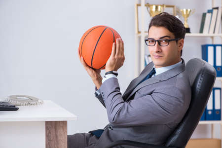 Young businessman playing basketball in office during breakの写真素材