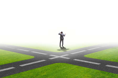 Young businessman at crossroads in uncertainty conceptの写真素材