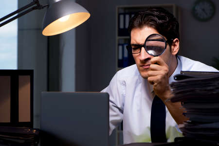 Young businessman working overtime late in officeの写真素材