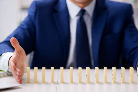 Young businessman playing with domino in officeの写真素材