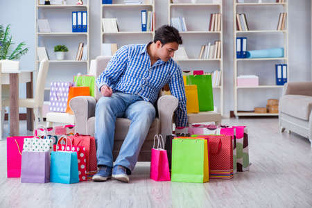 Young man after excessive shopping at homeの写真素材