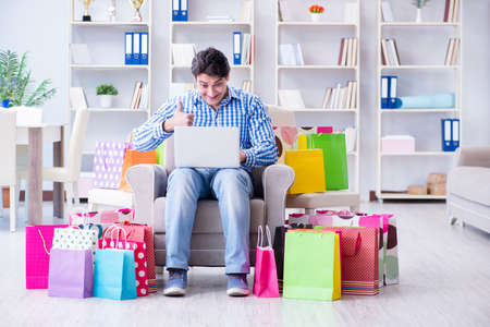 Young man after excessive shopping at homeの写真素材