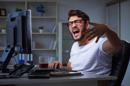 Young man staying late in office to do overtime workの写真素材