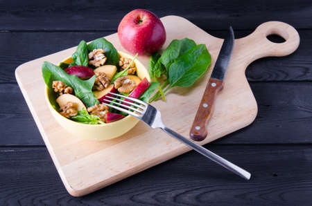 Spinach salad with nuts and apples served on tableの写真素材