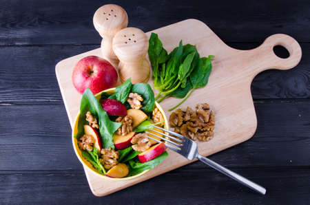 Spinach salad with nuts and apples served on tableの写真素材