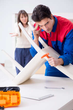 Contractor repairman assembling furniture under woman supervisioの写真素材