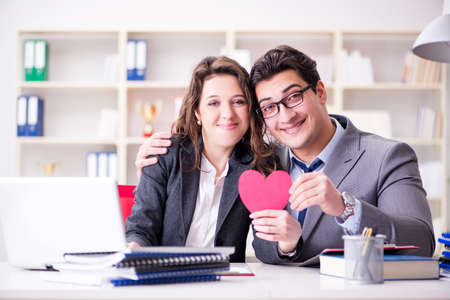 Happy couple working in the same officeの写真素材