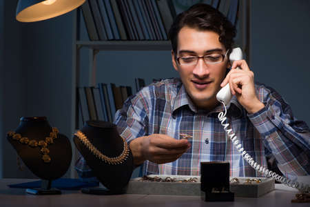 Young male jeweller working at night in his workshopの写真素材
